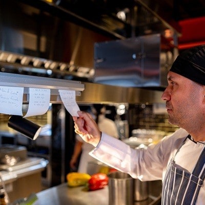Latin American chef looking at an order ticket while working in a commercial kitchen at a restaurant