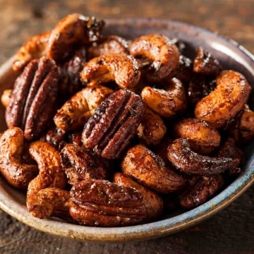 Frutos secos caramelizados, entre los que hay nueces pecaneras y anacardos, bien tostados y brillantes