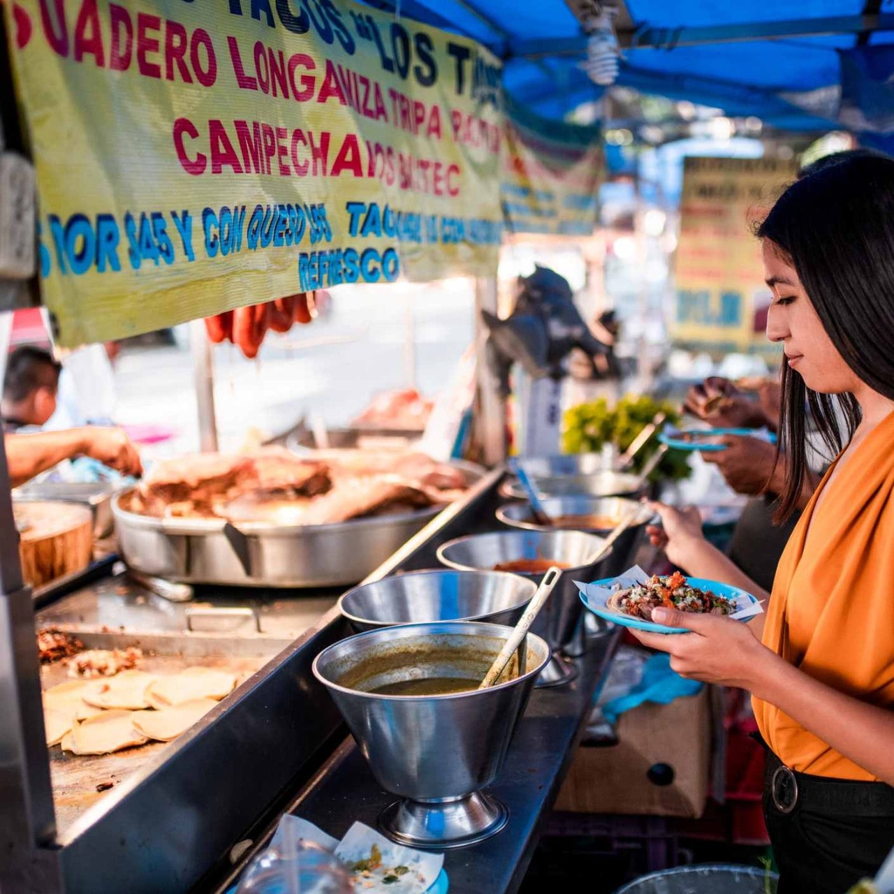 Mujer sirviéndose salsas en un puesto de comida callejera. Mujer sirviéndose salsas en un puesto de comida callejera.