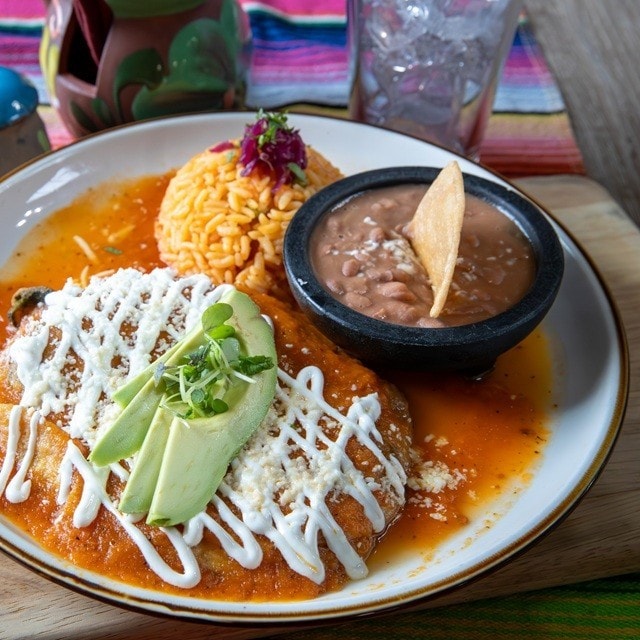 Plato fuerte con guarniciones, incluyendo enchiladas de pollo con arroz y frijoles. Plato fuerte con guarniciones, incluyendo enchiladas de pollo con arroz y frijoles.