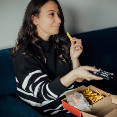 Mujer come en el sillón