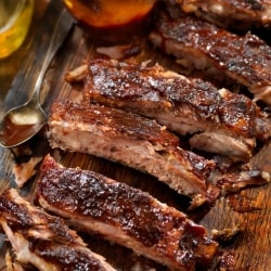 Costillas de cerdo estilo St. Louis con salsa barbecue, cocinadas a su punto perfecto y cortadas sobre una tabla. Costillas de cerdo estilo St. Louis con salsa barbecue, cocinadas a su punto perfecto y cortadas sobre una tabla.