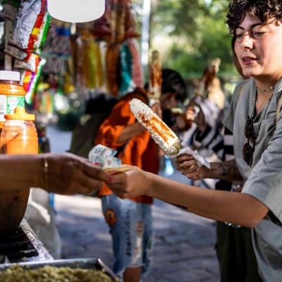 Mujer comprando comida en la calle, recibiendo algo horneado. Mujer comprando comida en la calle, recibiendo algo horneado.