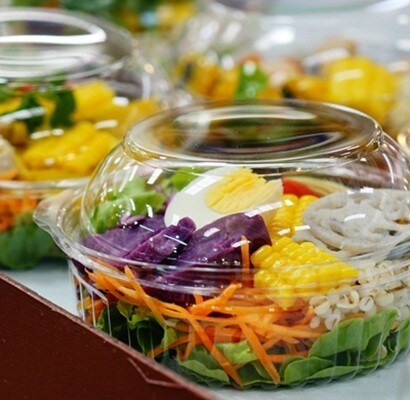 Salad of fresh vegetables and healthy fruit in clear plastic box  for sale in market