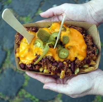 Poutine with French Fries and Chili con Carne on street food festival. Poutine fries are sold on Open kitchen food festival event. Street food in food stall.