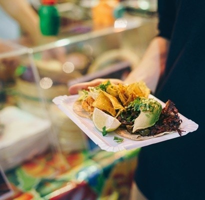 Man eating tacos at a street food market at night