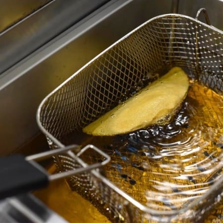 tortilla de maíz cocinándose en freidora con aceite caliente