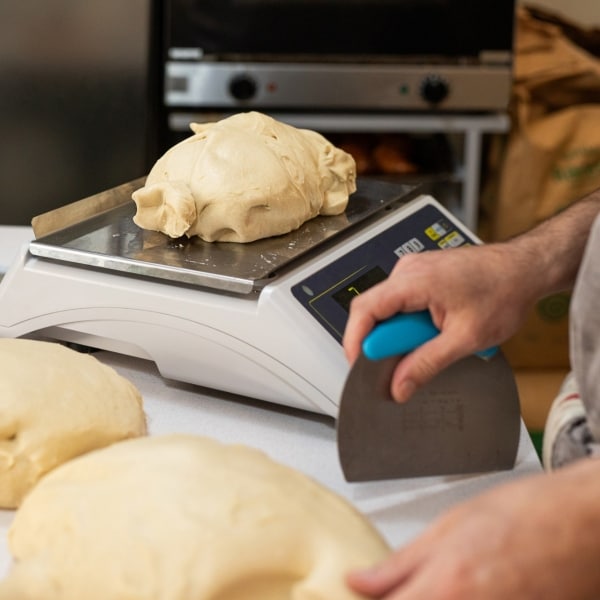 Unrecognizable person cutting and weighing fresh yeast dough for bread - Buenos Aires - Argentina