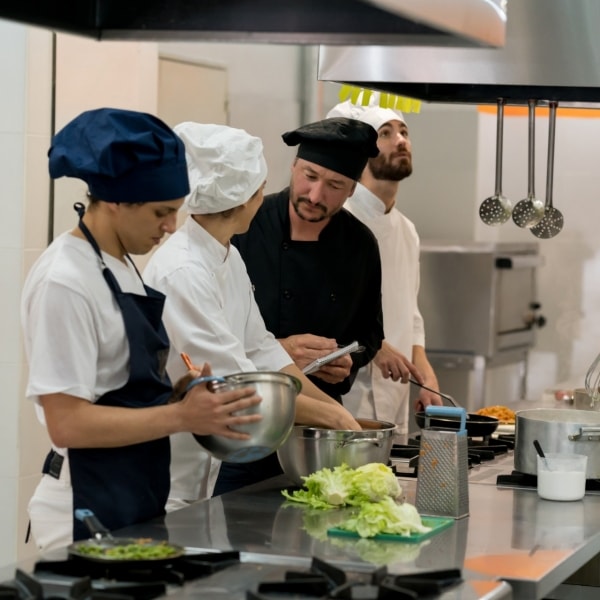 Chef and sous chef making a list of things to purchase while everyone else is working on their station looking very focused