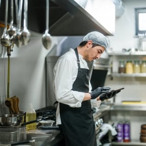 Chef gestionando inventario con software en una tablet. Chef gestionando inventario con software en una tablet.