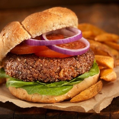 A fantastic vegetarian burger made with quinoa, chick peas, rolled oats, crushed onions and garlic, spices on a Whole Wheat Bun with spinach, tomatoes and onion and a side of Oven Baked French Fries -Photographed on Hasselblad H3D2-39mb Camera