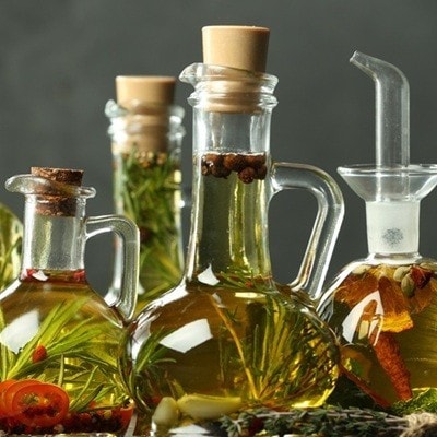 Cooking oil with different spices and herbs in bottles against grey background