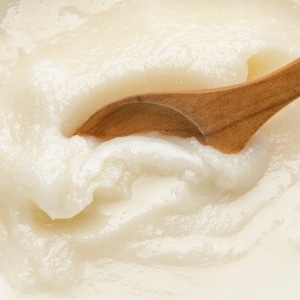 Con una cuchara de madera, una persona remueve la manteca de cerdo blanca y cremosa.