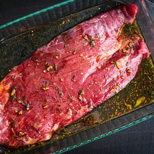 corte de carne de ternera en una fuente de vidrio sumergida en un líquido para marinado de carne. corte de carne de ternera en una fuente de vidrio sumergida en un líquido para marinado de carne.