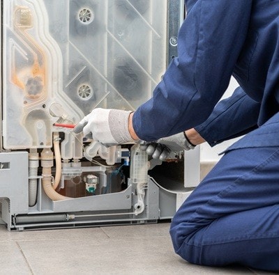 Shot of a young man repairing dishwasher in a home