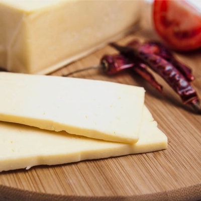 trozo de queso Chihuahua o queso menonita de México sobre tabla de madera con ají seco 