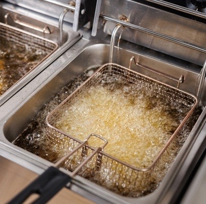 Frying potatoes in fryer for french fries in a restaurant