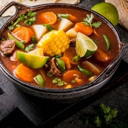 Olla de hierro con sopa en caldo rojo con trozos de carne de res y Olla de hierro con sopa en caldo rojo con trozos de carne de res y