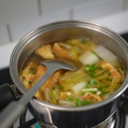 Un cocinero revuelve con un cucharón una sopa que prepara en la estufa usando una olla de acero inoxidable. La sopa lleva caldo, col blanca y tortillas, entre otros ingredientes. Un cocinero revuelve con un cucharón una sopa que prepara en la estufa usando una olla de acero inoxidable. La sopa lleva caldo, col blanca y tortillas, entre otros ingredientes.