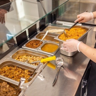 Caucasian female chef, preparing the metal trays with ingredients in the fast food restaurant kitchen